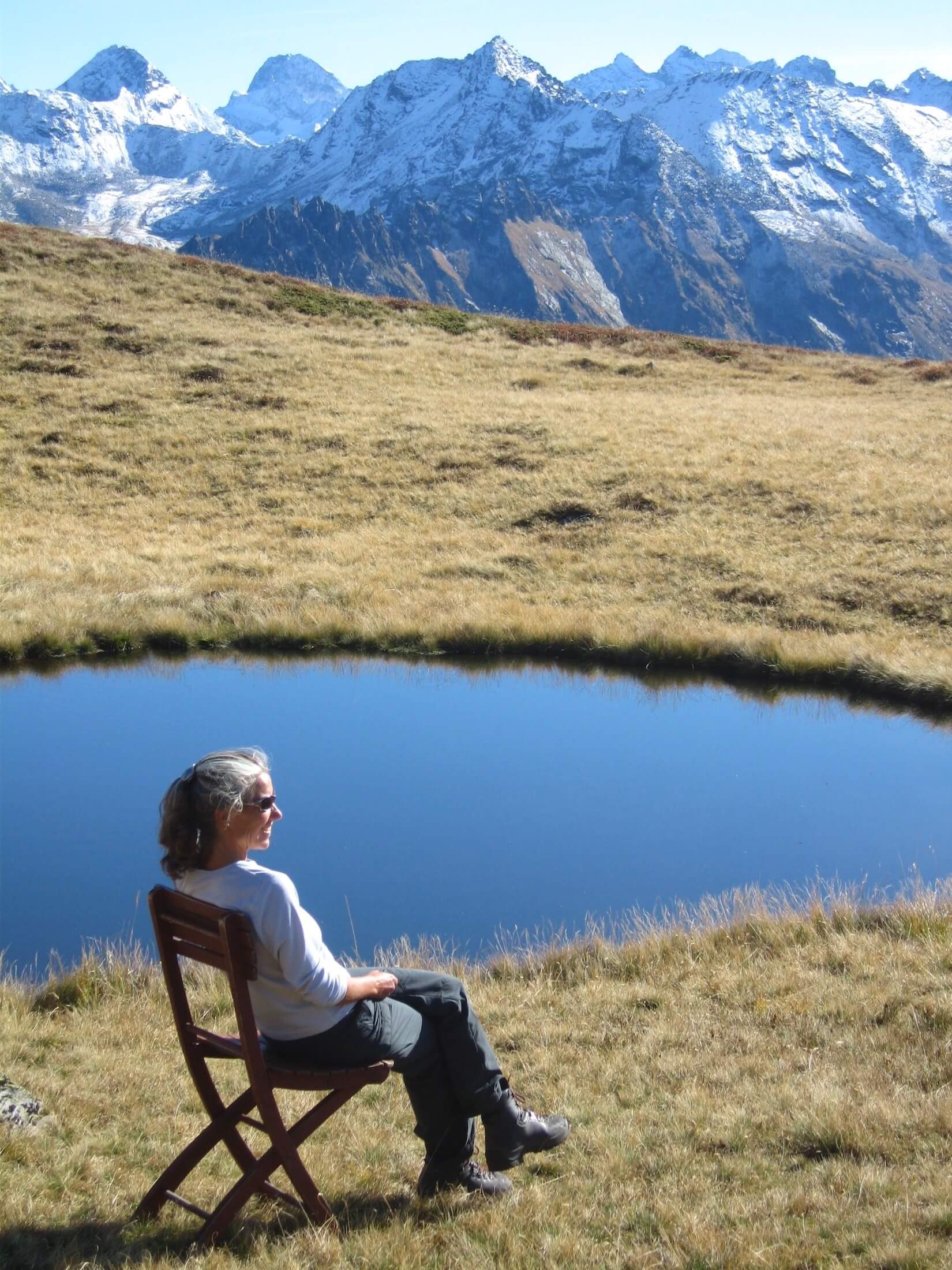 Eine Frau sitzt auf einem Stuhl und schaut auf die Berge
